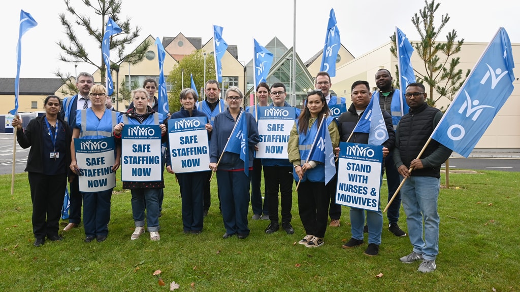 Large number of nurses holding signs outside hospital